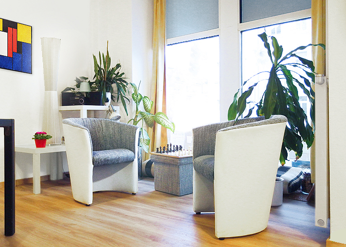 Zwei Sessel vor dem Fenster. In der Mitte ein kleiner Tisch mit einem Schachspiel vor dem Fenster.